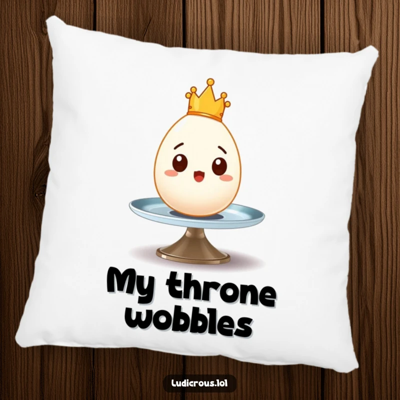 Funny pillow featuring a surprised egg with a tiny crown wobbling precariously on a spinning plate, offering royal comfort.