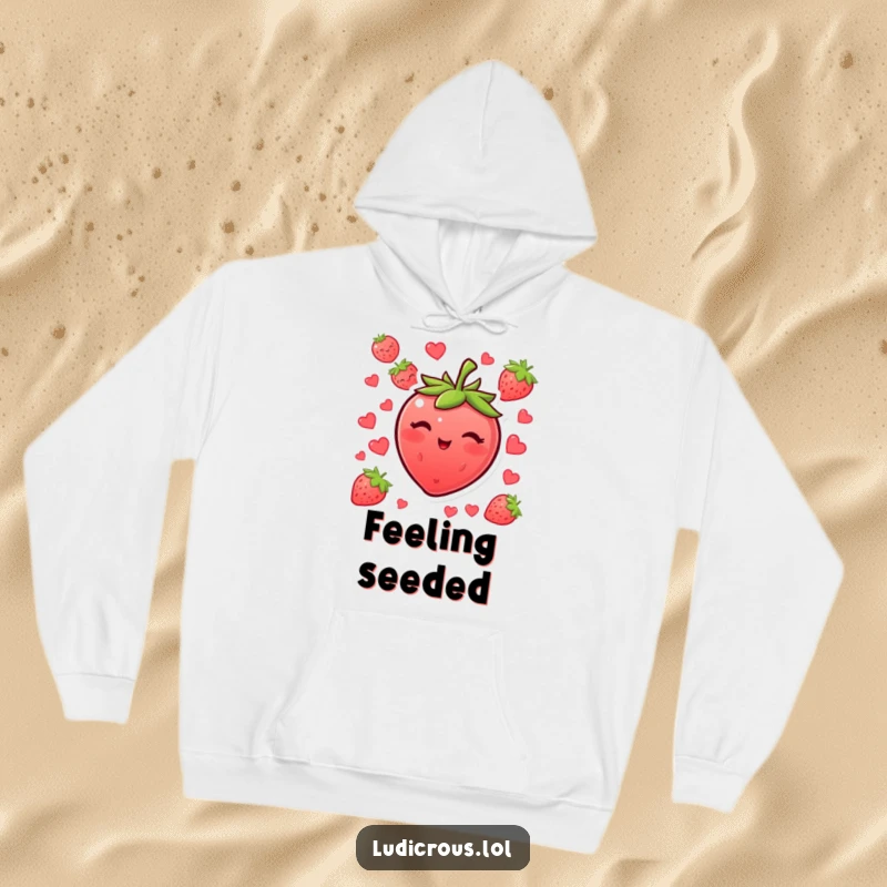 Funny blushing strawberry hoodie winking with its seeds, a cozy and humorous piece of apparel.