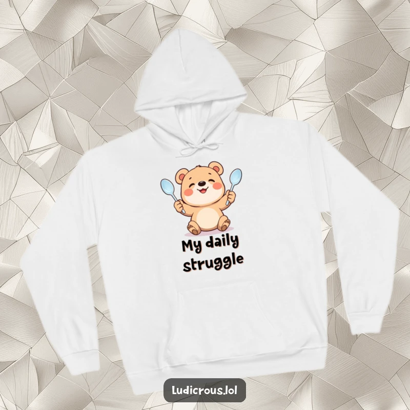 Funny hoodie design showing a smiling bear cub struggling to juggle bent spoons. Cozy apparel that highlights effort and humor.